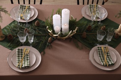 Photo of Christmas table setting with burning candles and other festive decor