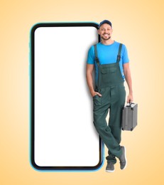 Repair service - just call. Happy professional repairman holding toolbox and smartphone with blank screen on beige background, space for design