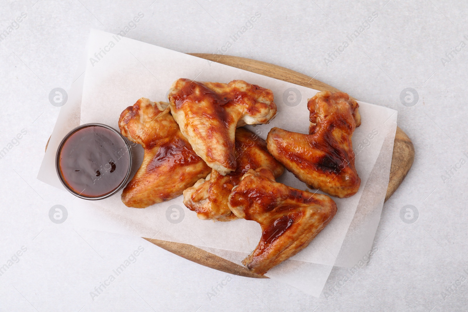 Photo of Board with marinade and chicken wings on light table, top view