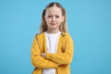 Portrait of sad girl on light blue background