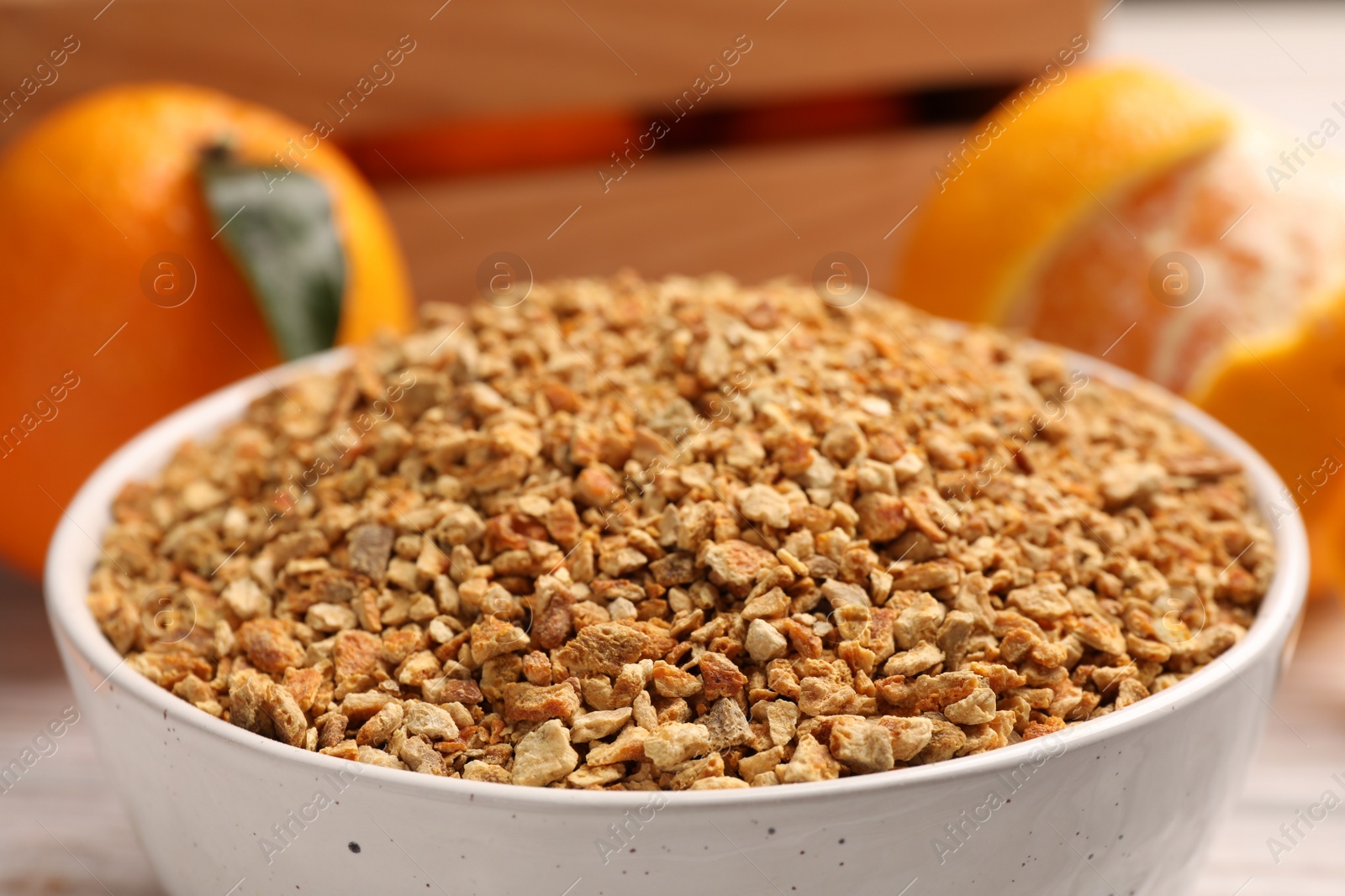 Photo of Bowl with dried orange seasoning zest and fruits on table, closeup