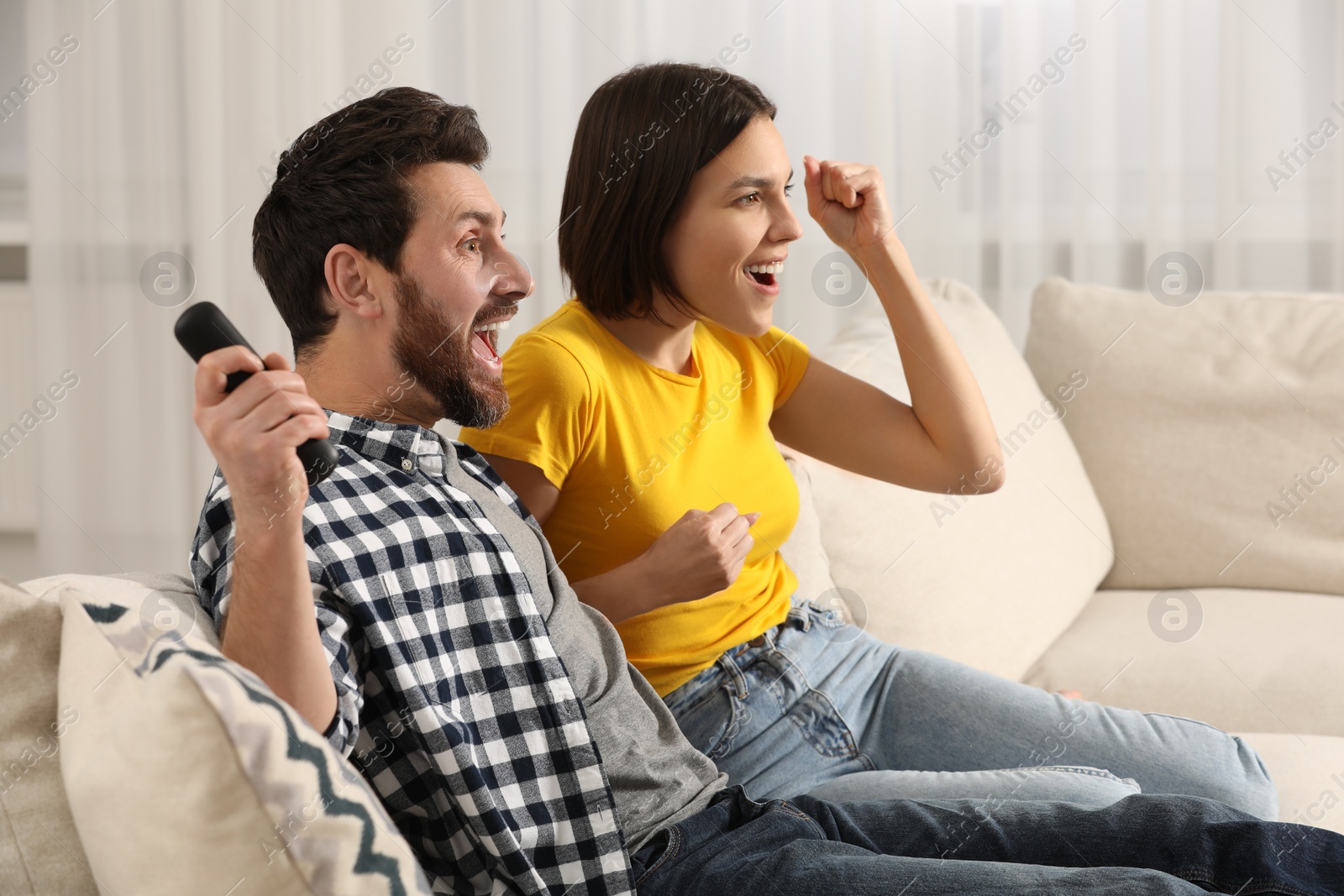 Photo of Happy couple watching TV on sofa at home