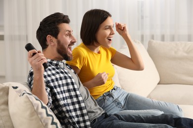 Photo of Happy couple watching TV on sofa at home