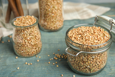 Uncooked green buckwheat grains on light blue wooden table