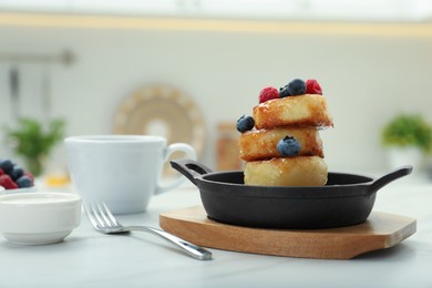 Delicious cottage cheese pancakes with fresh berries and honey served on white table. Space for text