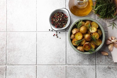 Flat lay composition with tasty baked potato and aromatic rosemary on white tiled table. Space for text