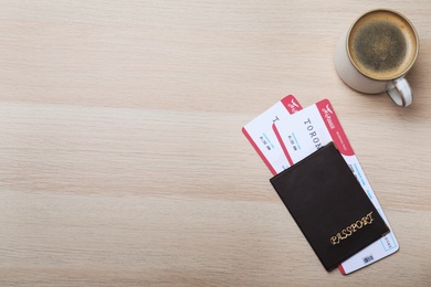 Photo of Avia tickets, passport and cup of coffee on wooden table, flat lay with space for text. Travel agency concept