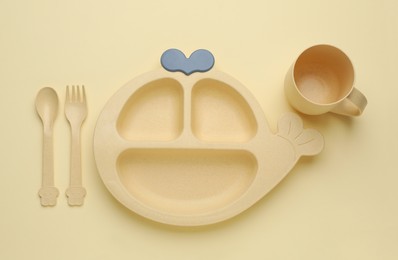 Photo of Set of plastic dishware on beige background, flat lay. Serving baby food