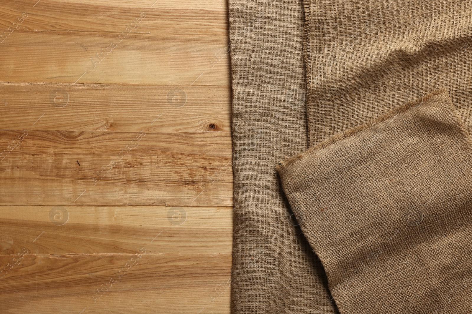 Photo of Burlap fabric on wooden table, top view. Space for text