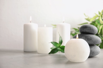 Photo of Beautiful spa composition with candles and stones on table, space for text