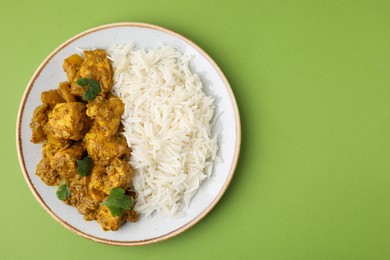 Photo of Delicious chicken curry with rice on green background, top view. Space for text