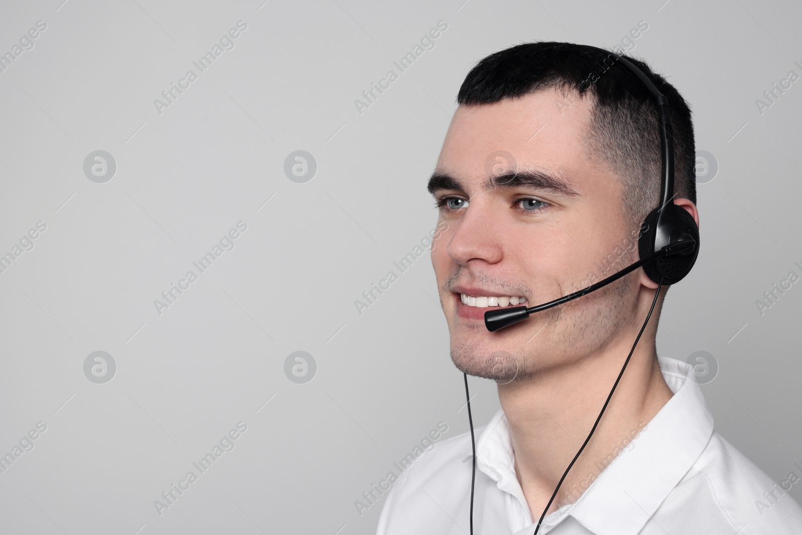 Photo of Hotline operator with headset on light grey background, space for text