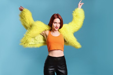 Stylish woman with red dyed hair on light blue background