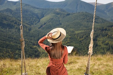 Young woman reading book in mountains, back view