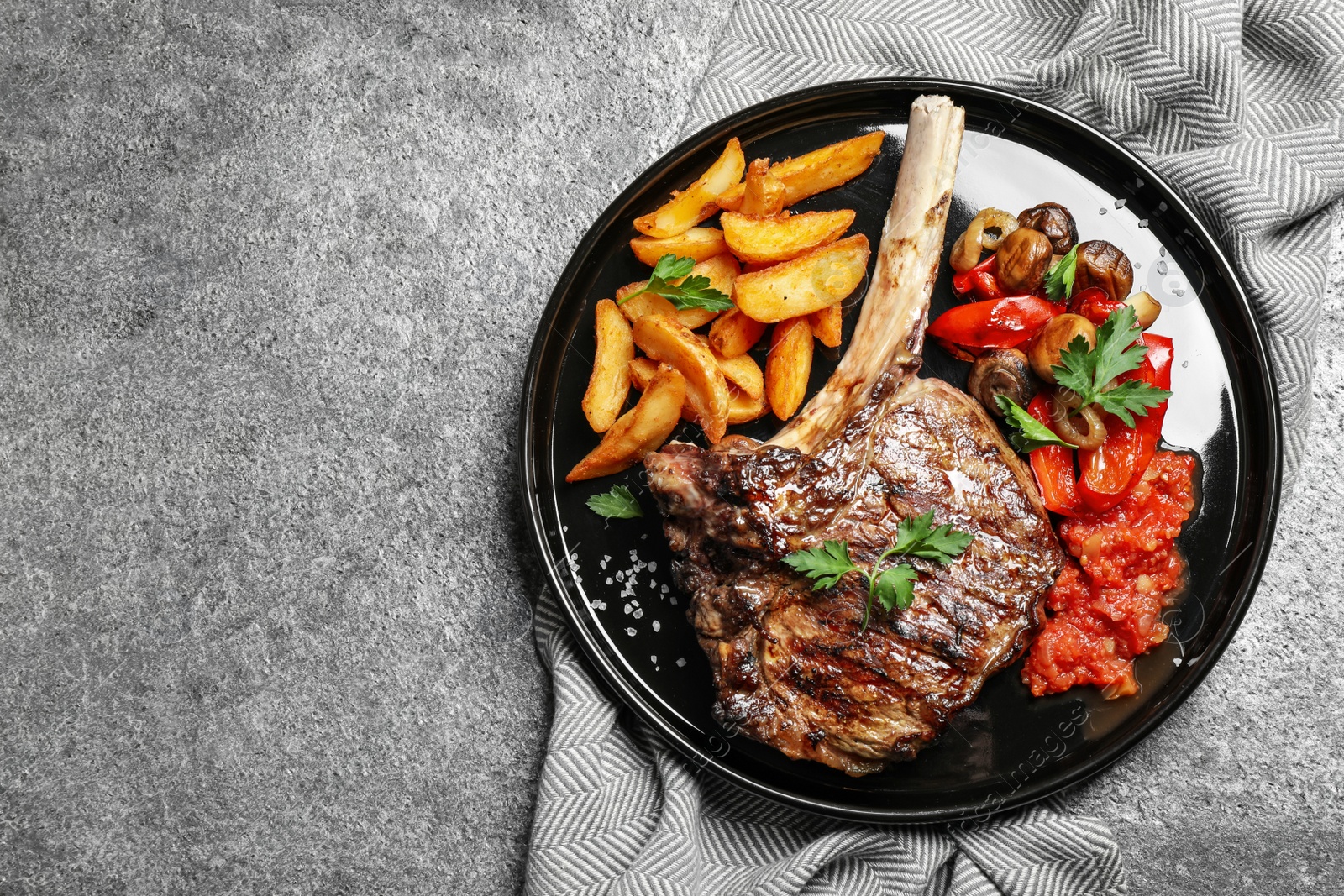 Photo of Delicious grilled ribeye served on grey table, flat lay. Space for text