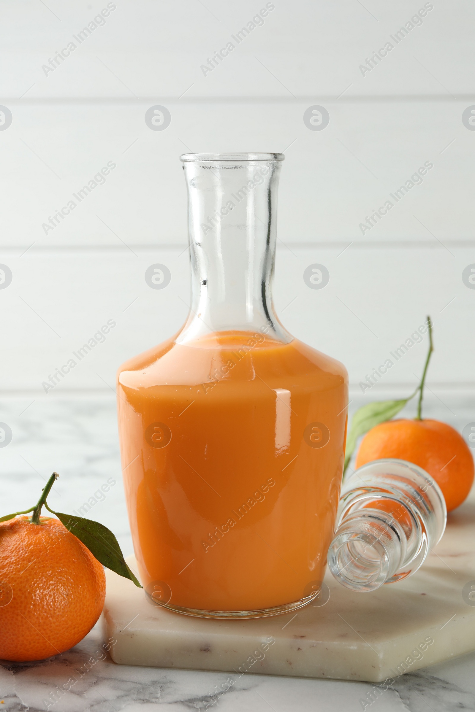 Photo of Delicious tangerine liqueur and fresh fruits on white marble table