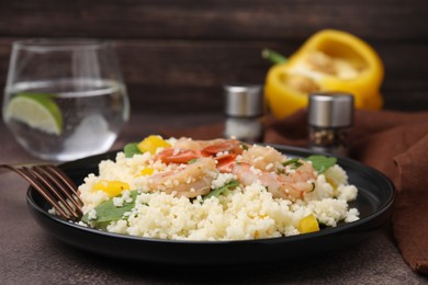 Photo of Tasty couscous with shrimps, bell pepper and basil on brown textured table, closeup