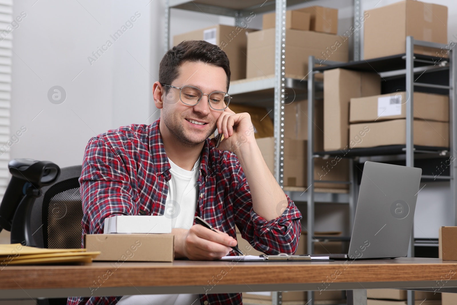 Photo of Seller talking on phone while working in office. Online store