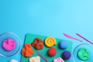 Photo of Flat lay composition with colorful plasticine on light blue background. Space for text
