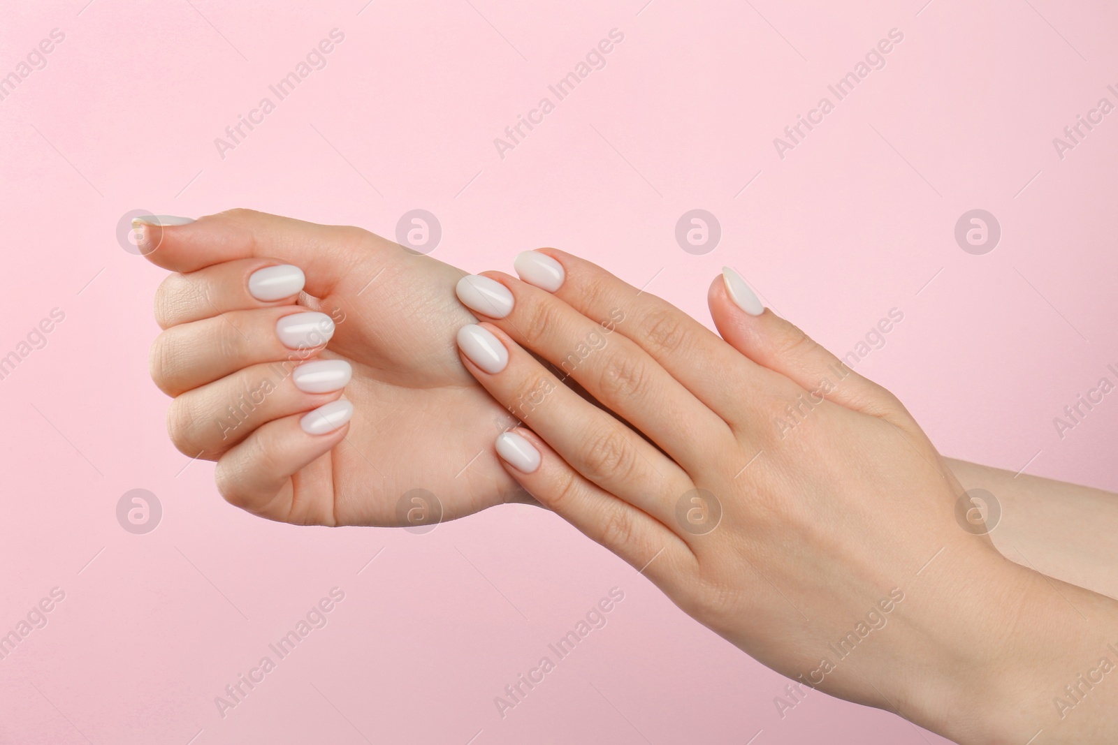 Photo of Woman with white polish on nails against pink background, closeup