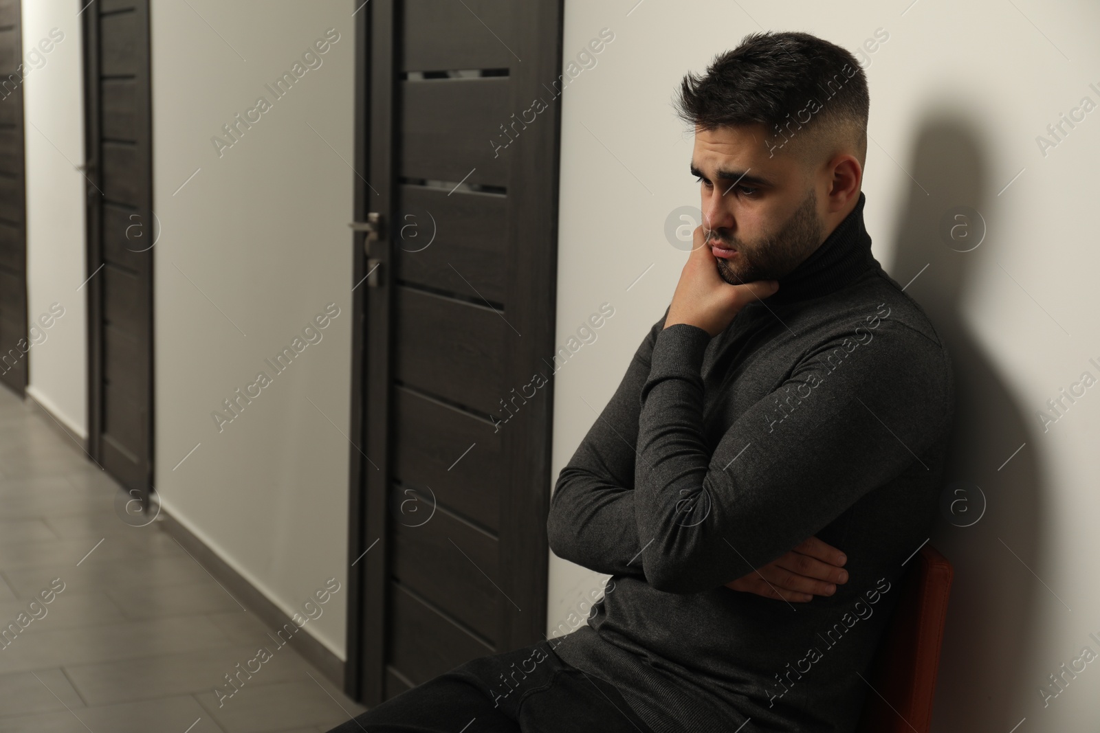 Photo of Sad young man in hall. Space for text