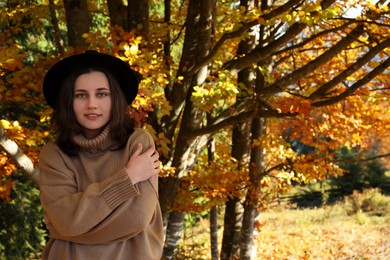Photo of Portrait of beautiful young woman with hat in autumn forest. Space for text