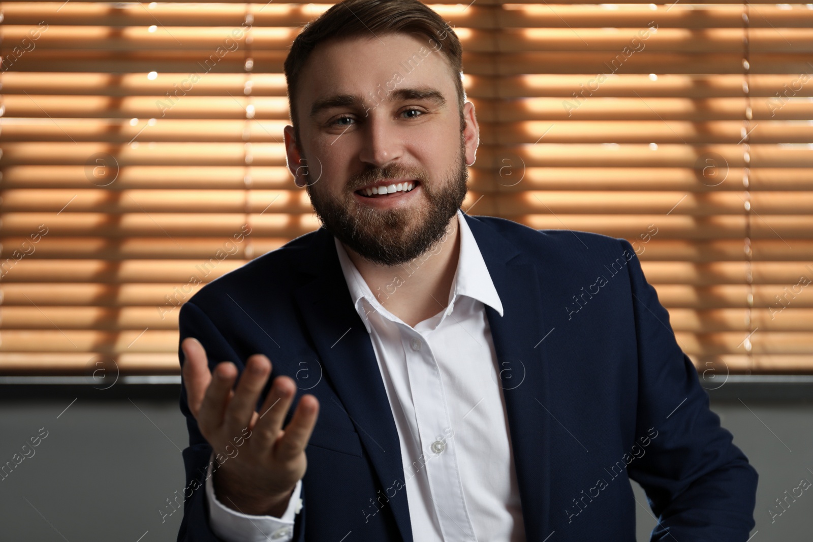 Photo of Young man in suit holding online webinar indoors, view from webcam