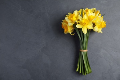 Photo of Bouquet of daffodils on dark background, top view with space for text. Fresh spring flowers