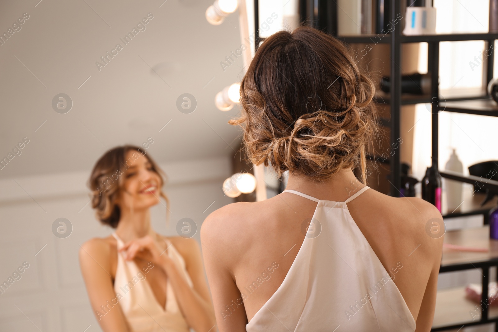 Photo of Woman with beautiful hairstyle near mirror in salon