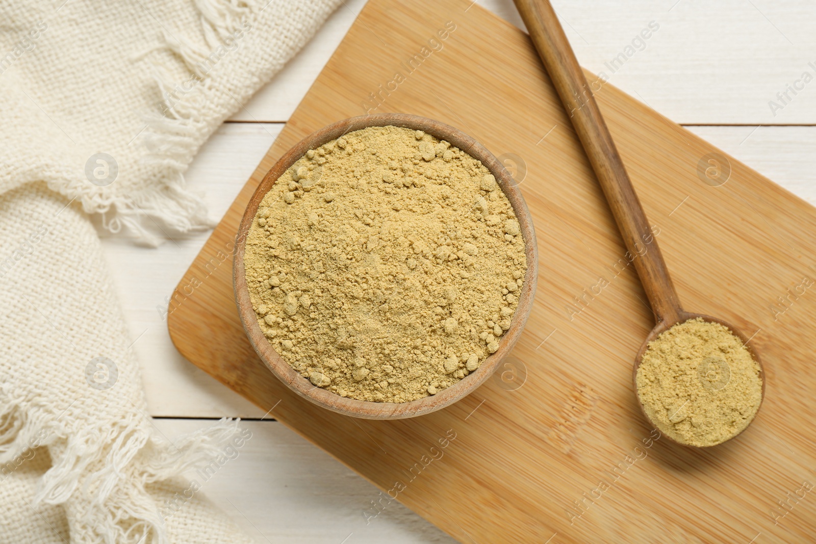 Photo of Bowl and spoon with aromatic mustard powder on white wooden table, flat lay