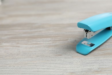 Photo of One light blue stapler on wooden table, closeup. Space for text