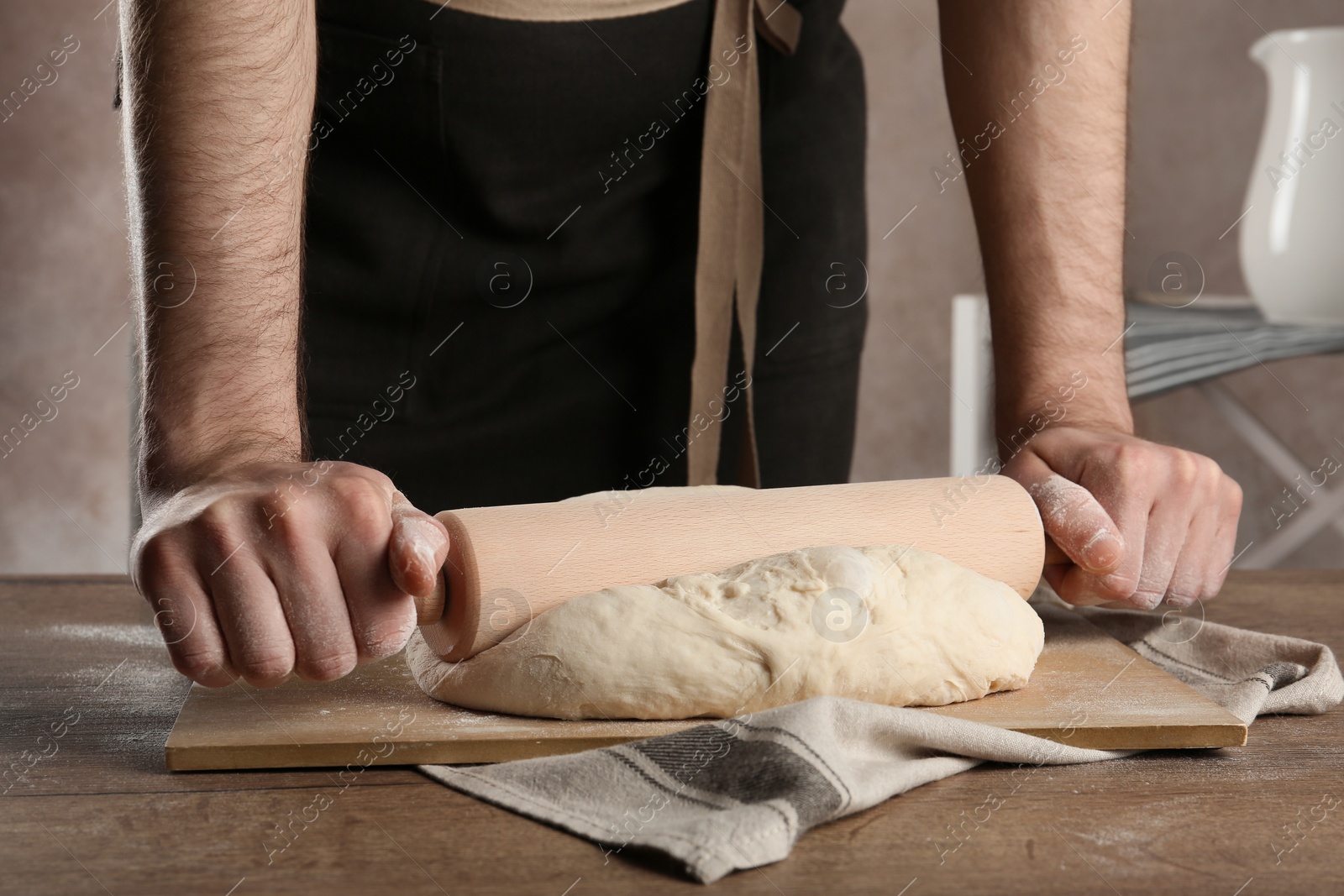 Photo of Male baker preparing bread dough at table, closeup