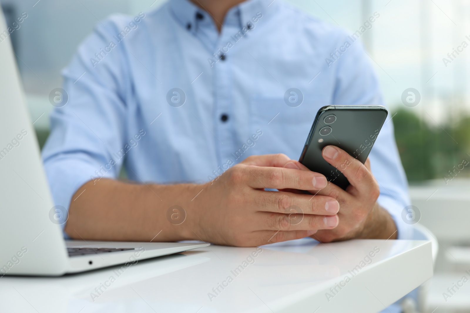 Photo of Man with smartphone and laptop in outdoor cafe, closeup