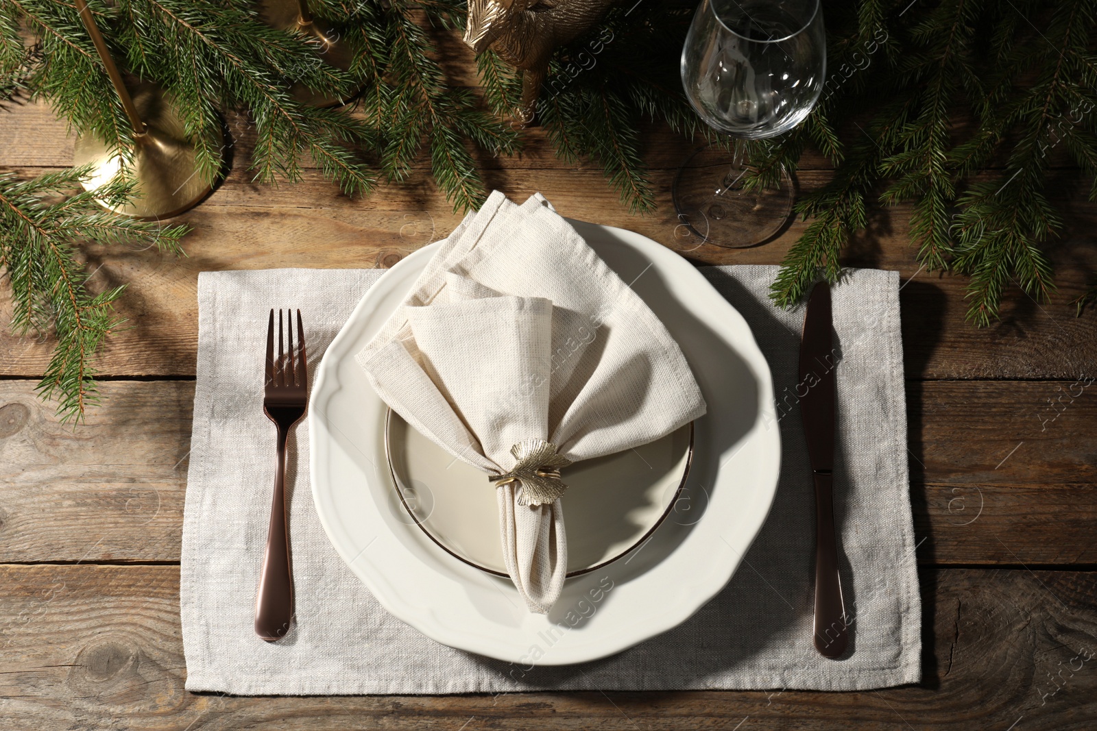 Photo of Stylish table setting with white fabric napkin, beautiful decorative ring and festive decor on wooden background, flat lay