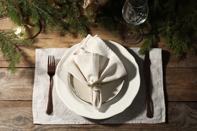 Photo of Stylish table setting with white fabric napkin, beautiful decorative ring and festive decor on wooden background, flat lay