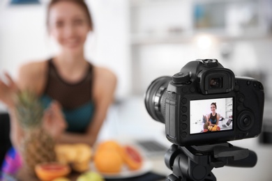 Photo of Female blogger with fruits on camera screen, closeup