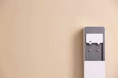 Photo of Modern water cooler against color background with space for text