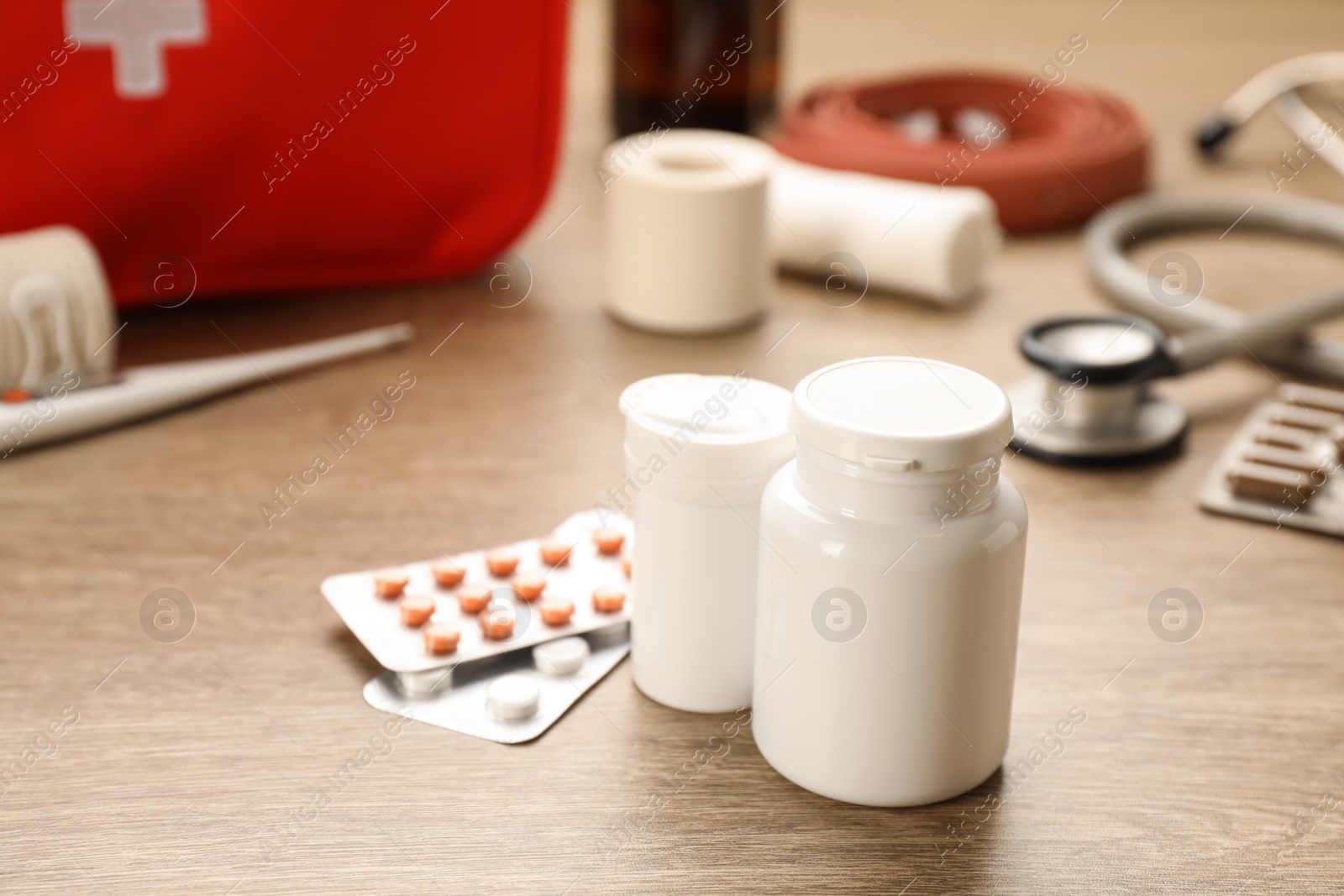 Photo of Different pills on wooden table, closeup. First aid kit