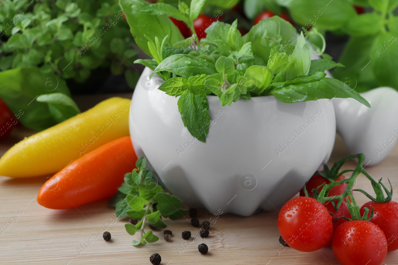 Photo of Mortar with different fresh herbs and pepper on wooden table, closeup