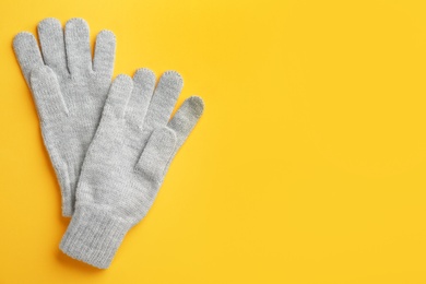 Pair of stylish woolen gloves on yellow background, flat lay. Space for text