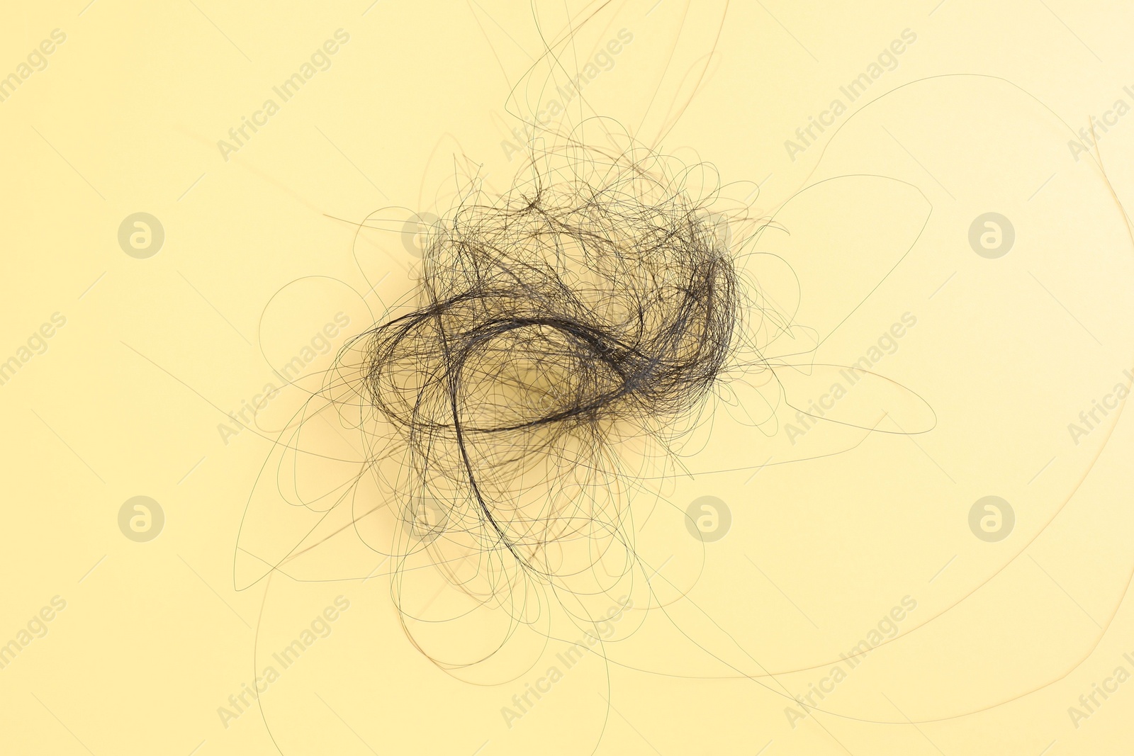 Photo of Pile of lost hair on yellow background, top view