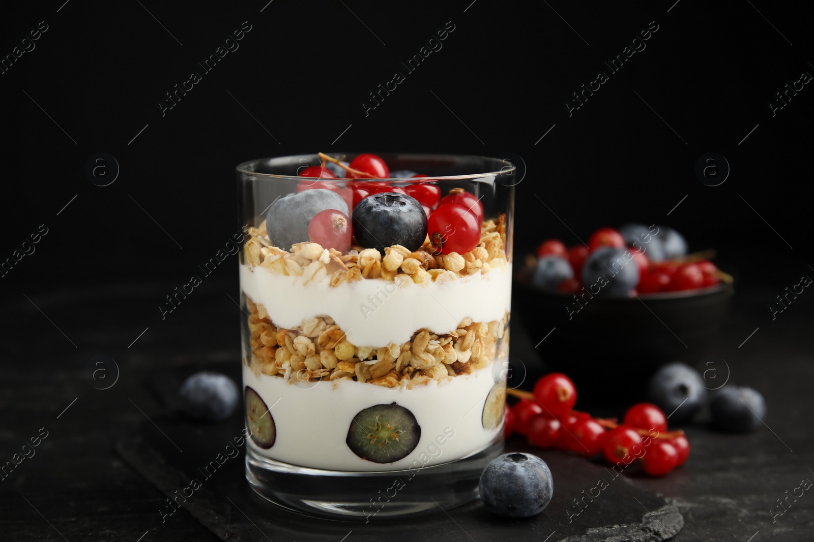 Photo of Delicious yogurt parfait with fresh berries on black table, closeup