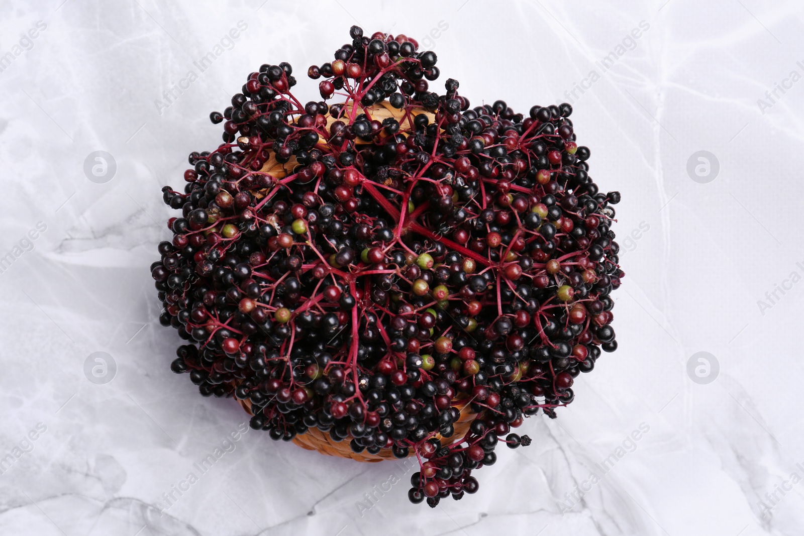 Photo of Tasty elderberries (Sambucus) on white marble table, top view