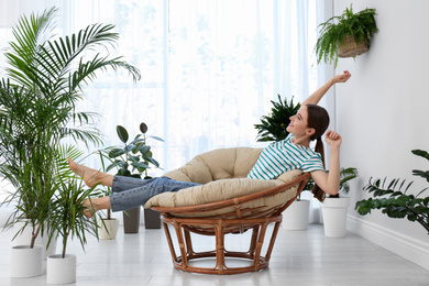 Photo of Young woman in room decorated with plants. Home design
