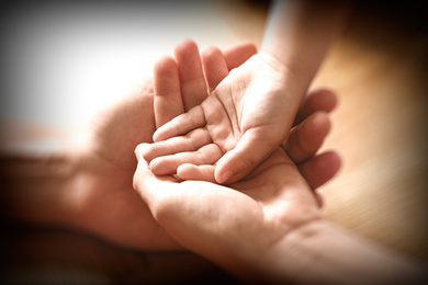 Happy family holding hands on wooden background, closeup