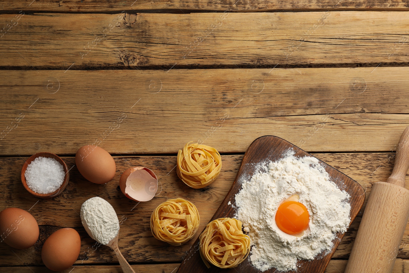 Photo of Raw noodles and ingredients on wooden table, flat lay. Space for text