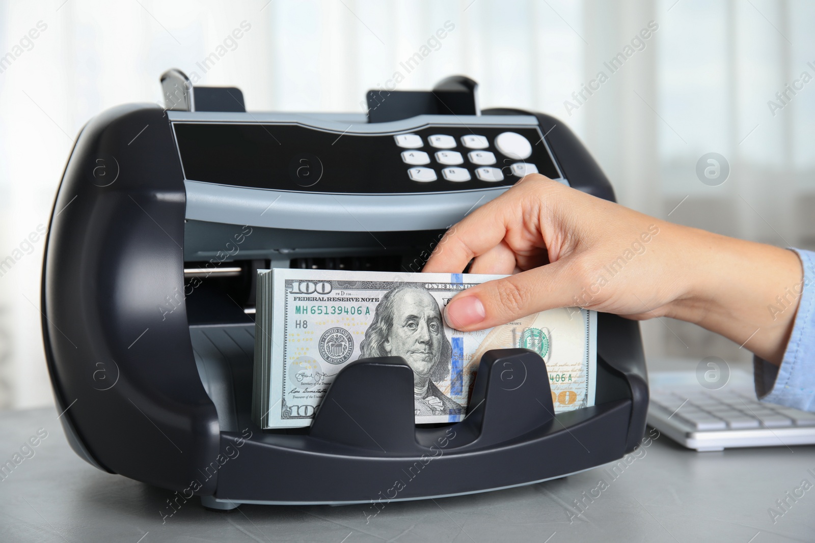 Photo of Woman taking money from counting machine at table indoors, closeup