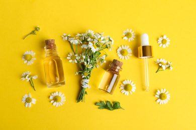 Flat lay composition with chamomile essential oil on yellow background