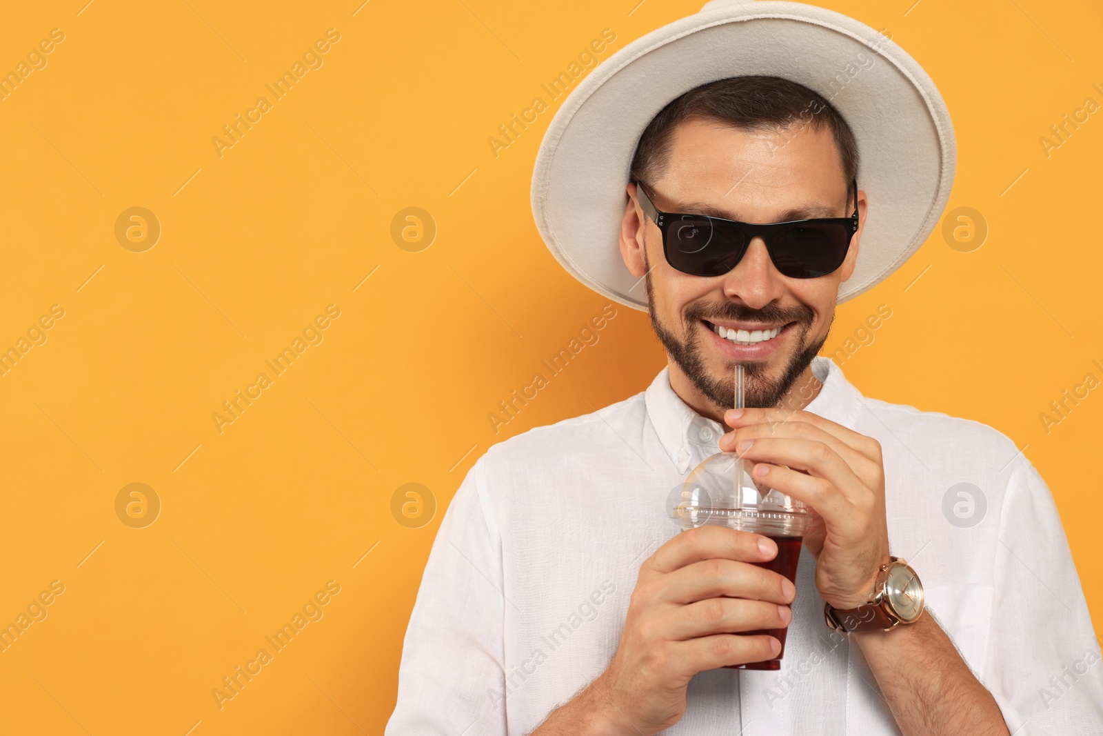 Photo of Man drinking delicious juice on orange background, space for text