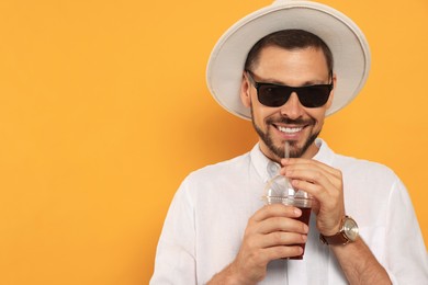 Photo of Man drinking delicious juice on orange background, space for text